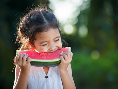 A photo of a girl eating a watermelon